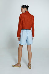 Blazer Diana laranja feminino com caimento ajustado e Bermuda Escada azul claro com caimento reto e solto sem bolsos atrás.