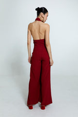 Macacão vermelho com decote torcido, alças cruzadas e calça ampla.