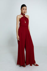 Macacão vermelho com decote torcido e calça pantalona fluida.