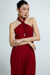 Macacão vermelho com decote torcido, alças cruzadas e calça pantalona.