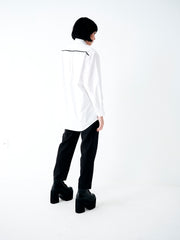 Camisa branca feminina com modelagem ampla, ombros estruturados e caimento fluido em algodão.