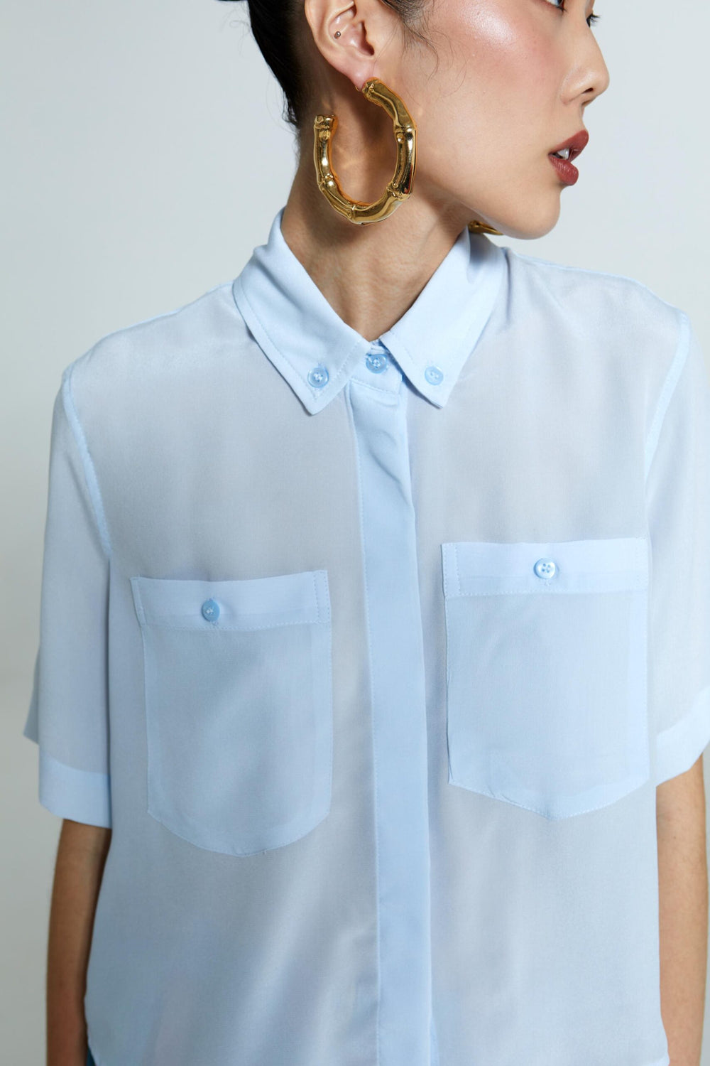 Camisa Emma feminina azul de seda com mangas curtas, modelagem reta e tecido levemente translúcido