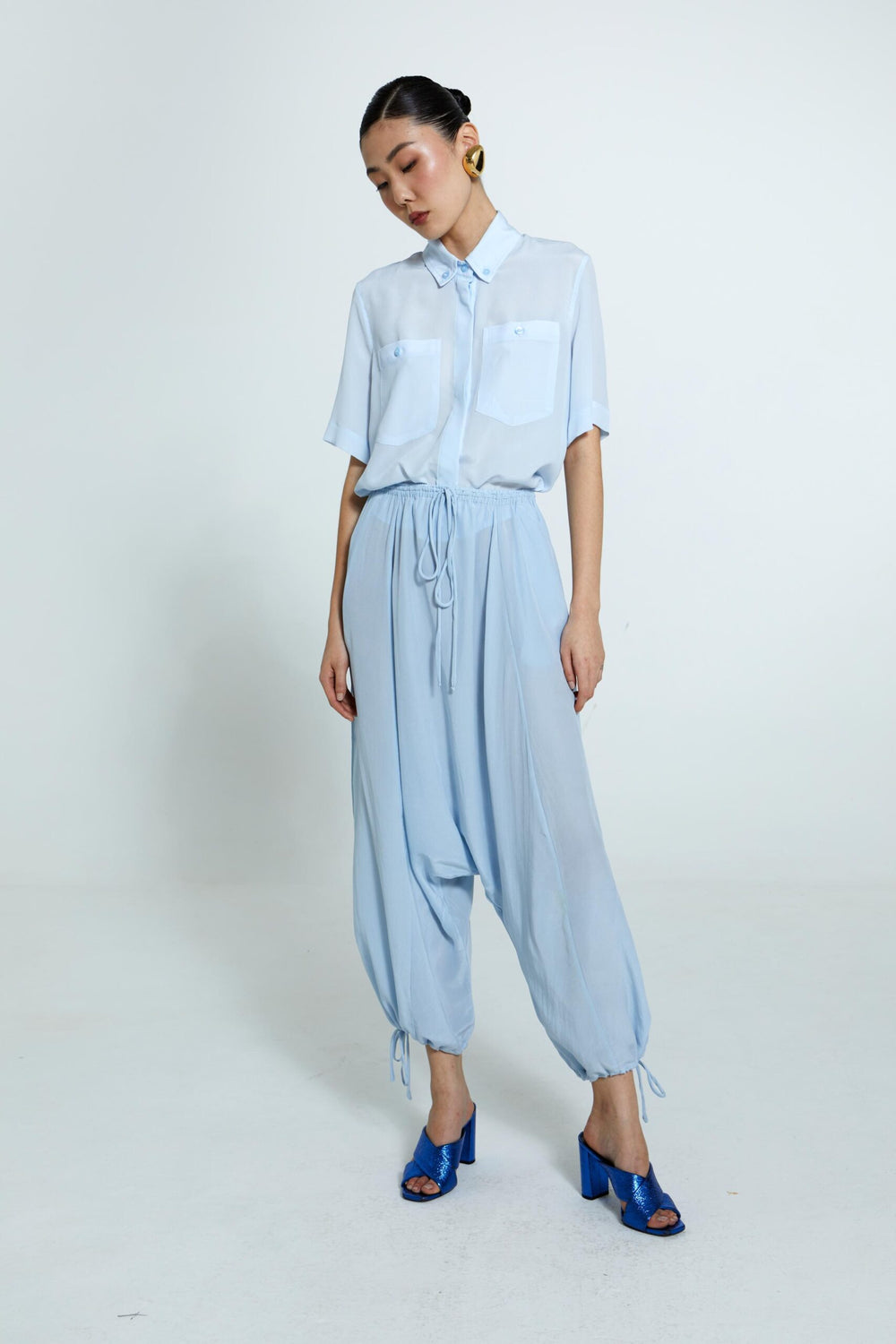 Camisa Emma feminina de seda azul com transparência sutil e caimento fluido.