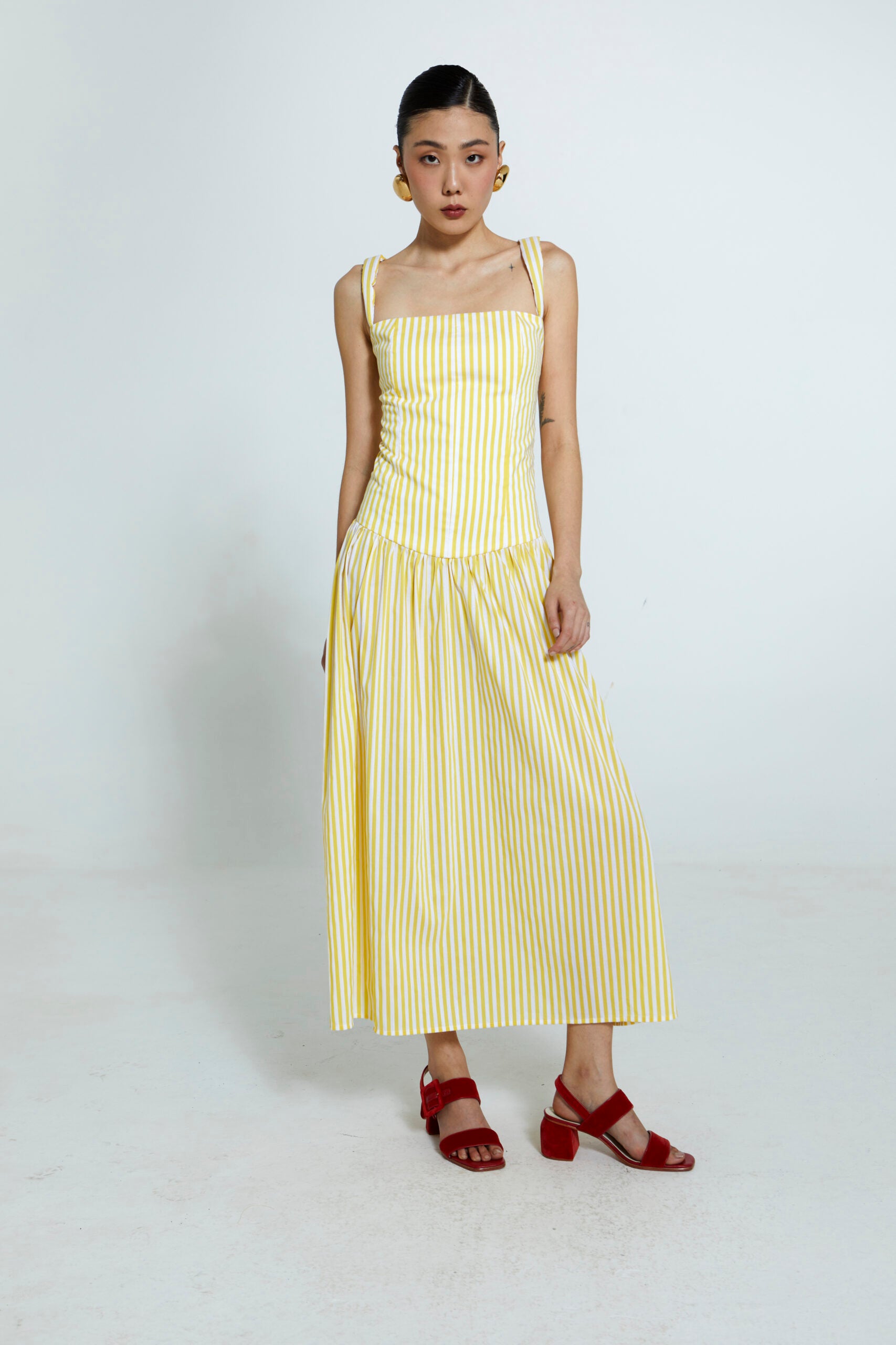 Vestido amarelo com listras brancas e saia franzida.