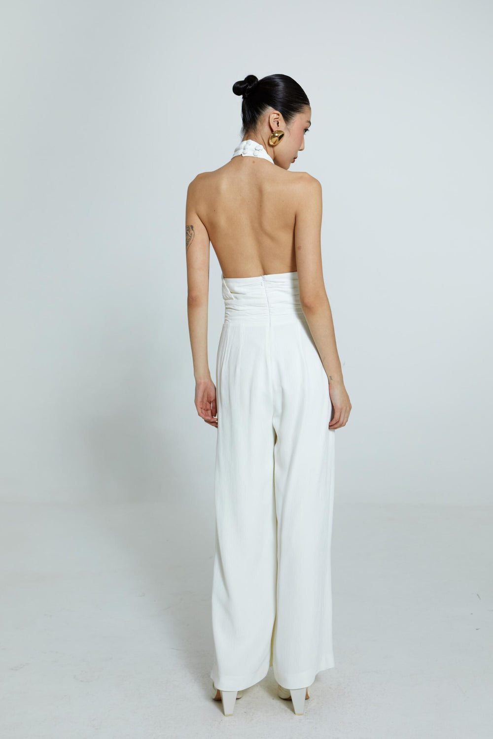 Macacão off-white com decote torcido e alças finas.