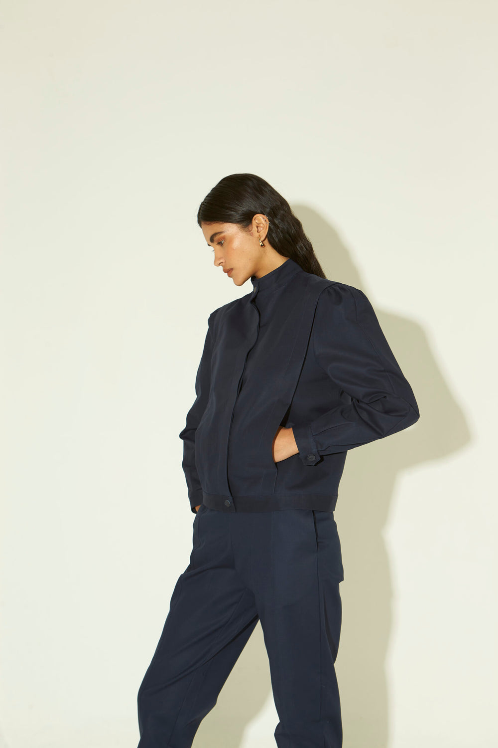 Jaqueta feminina em algodão azul marinho com mangas volumosas, gola alta e fechamento frontal.