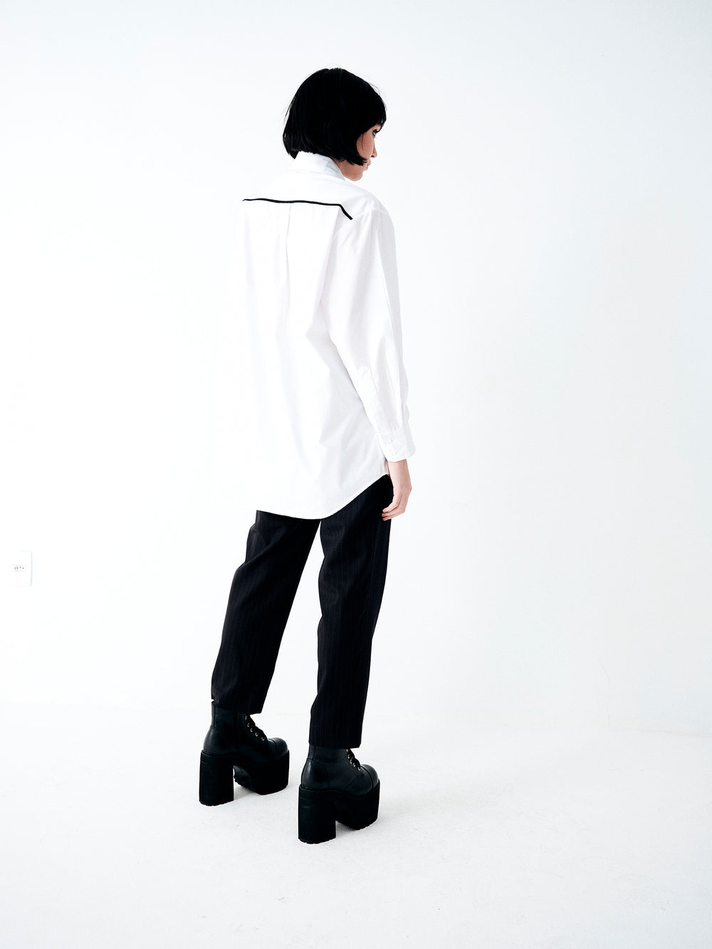 Camisa branca feminina com modelagem ampla, ombros estruturados e caimento fluido em algodão.